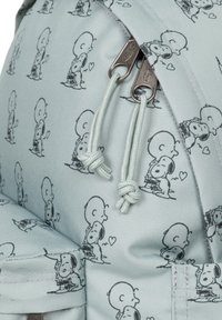 Ljusblå tygryggsäck med ett upprepat svart tecknat mönster av Charlie Brown och Snoopy. Reglerbara snören med metalldetaljer.