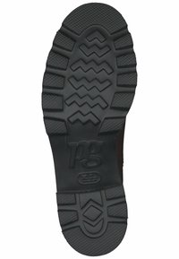 Suela de zapato de goma negra con patrones texturizados, que presenta agarres en zigzag y circulares, y un logo en relieve "pg" cerca de la zona del talón.