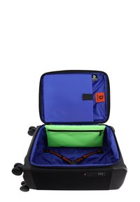 Valigia nera con guscio rigido. Gli interni presentano una fodera blu, un compartimento verde imbottito e accenti arancioni. Include ruote e un lucchetto.