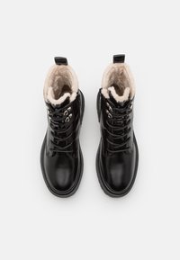 Černé kožené šněrovací boty s měkkou krémovou podšívkou a robustní podrážkou, s kovovými detaily a poutkem na zadní straně pro snadné obouvání.