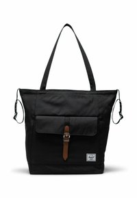 Sac fourre-tout noir avec de longues poignées, poche à rabat avant fixée par une boucle en cuir marron, et petite étiquette de marque blanche près du bas.