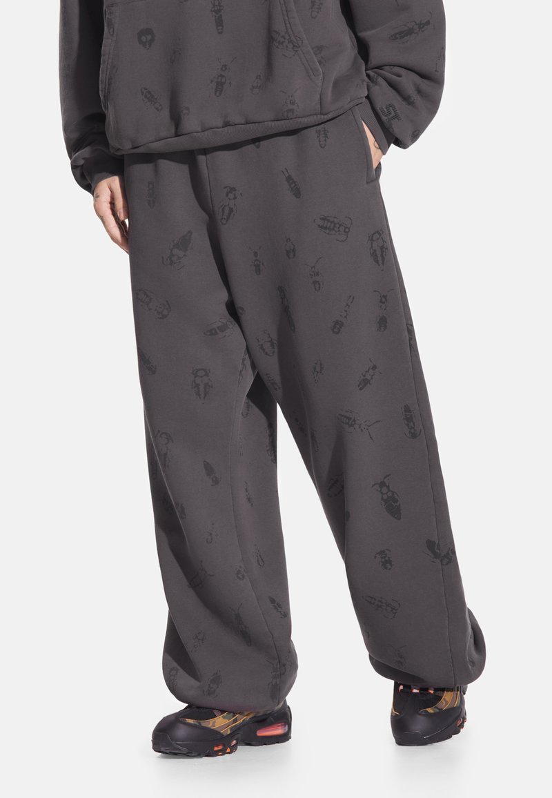 Ciemnoszare spodnie dresowe o luźnym kroju, z nadrukiem rozrzuconych owadów i elastycznym pasem. Wykonane z miękkiego materiału.