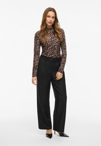 Brown leopard print long-sleeve top paired with high-waisted black wide-leg trousers and pointed black heels. Smooth texture throughout.