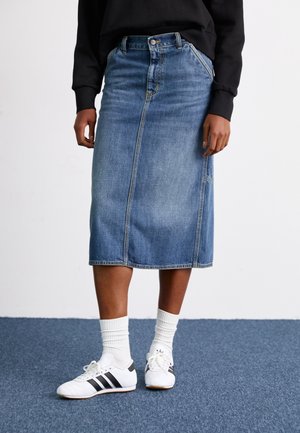 Denim midi-rok in lichtblauw met een rechte snit, voorzien van voorpassen en gecombineerd met witte sneakers en geribbelde sokken.