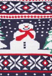 Tissu tricoté avec un bonhomme de neige souriant portant une écharpe rouge, entouré de flocons de neige et de sapins verts sur un fond bleu marine.