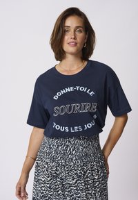 Tricou din bumbac de culoare bleumarin, cu mâneci scurte, având text brodat alb. Asortat cu o fustă cu imprimeu, care prezintă un brâu texturat.