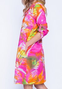 Farverig knælang kjole lavet af let materiale, med et levende tropisk print med pink, orange og grønne blade. Inkluderer sidelommer.