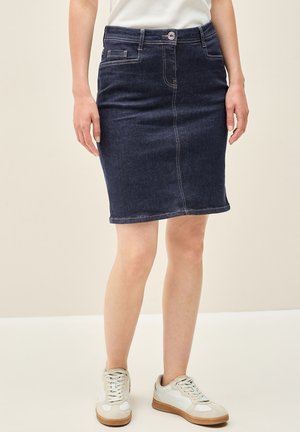 Dark denim pencil skirt with a fitted shape, front pockets, and visible stitching details. Paired with casual white sneakers.
