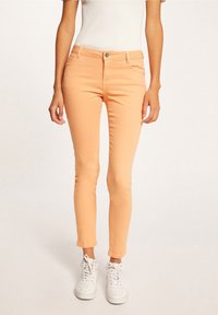 Růžové skinny džíny vyrobené z denimu, s klasickým pětipocket designem, zipovým zapínáním na knoflík a délkou do kotníků.