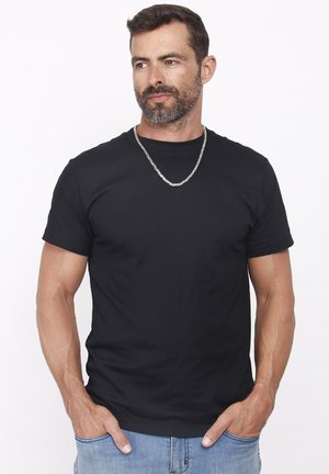 Mustast puuvillast lühikeste varrukatega ümara kaelusega t-särk, millel on hõbedane kett-kaelakee. Kandmisel hele sinise värvusega teksased.