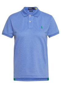 Ljusblå polo med krage, två vita knappar och en grön broderad logotyp. Korta ärmar med kontrasterande gröna detaljer i fållen.