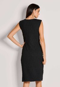 Schwarzes ärmelloses Kleid mit einem strukturierten Blattmuster, knielanger Schnitt und einer taillierten Passform, die eine glatte Silhouette und elegante Linien betont.