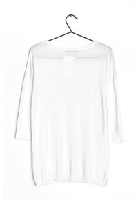 Witte lichtgewicht trui met driekwartmouwen, ronde hals en geribde zoom. Plat neergelegd en hangend aan een zwarte haak.