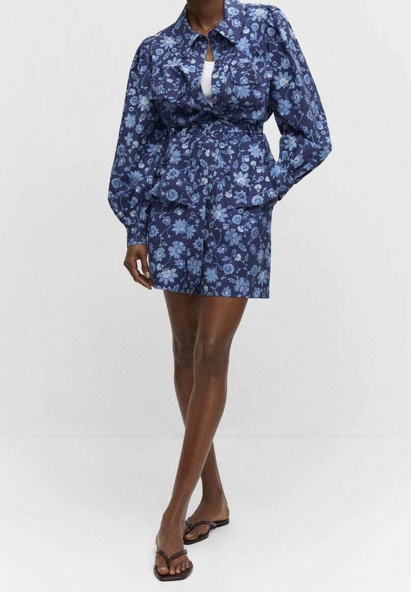Floral-patterned, navy blue two-piece outfit featuring a structured, puff-sleeved top with a cinched waist and matching shorts.