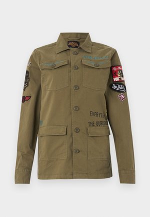 Oliwkowozielona kurtka w stylu wojskowym z zapinanym na guziki przodem, kieszeniami na piersi i dole oraz wieloma naszywkami i napisami na rękawach i piersi.