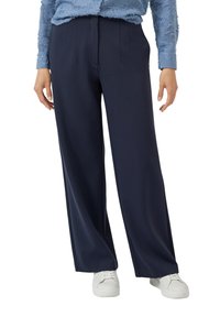 Granatowe spodnie o szerokich nogawkach z wysokim stanem, z przodu z zakładkami i gładką tkaniną. Dobierane do białych butów dla kontrastu.