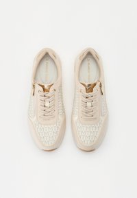 Baskets beiges dotées d'un dessus texturé avec un motif de logo répété, fermeture à lacets et un accent zippé sur le côté. Taille 37.