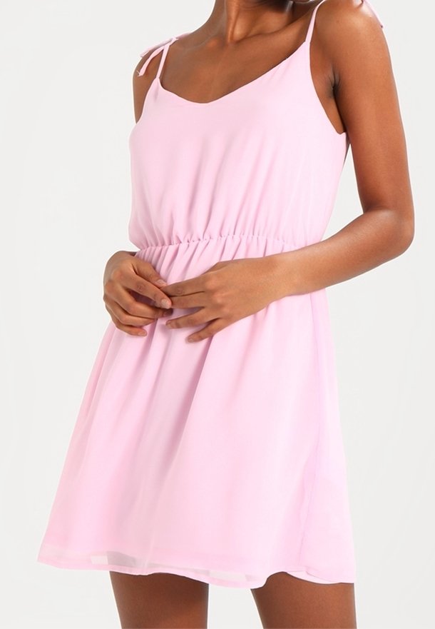 Robe rose clair sans manches avec de fines bretelles, un corsage ajusté et une taille froncée, en tissu doux et léger.