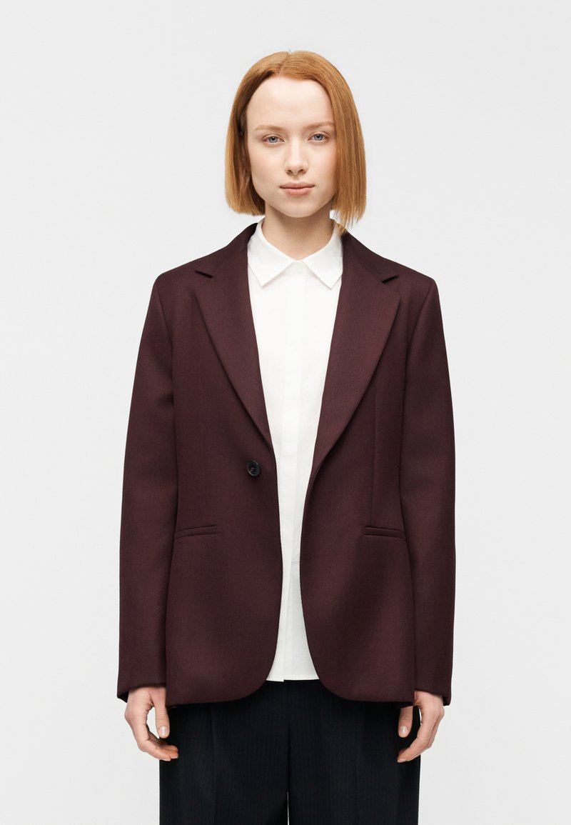 Μπορντό σακάκι με πέτο με εγκοπή, κλείσιμο με ένα κουμπί, δύο μπροστινές τσέπες, κομμένο εφαρμοστά, κατασκευασμένο από δομημένο ύφασμα.