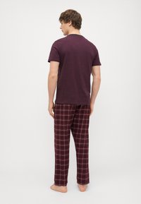 Burgundia lühikeste varrukatega t-särk ja tume punane, valge ja navy värvides ruuduline pliiatsipüksi, millel on lahtine lõige ja pehme materjal, kantud paljajalu.