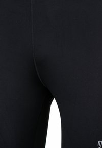 Zwarte sportleggings van rekbare stof. Heeft een glad oppervlak, een aansluitend ontwerp en contrasterende stiksels langs de naden.