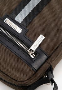 Borsa a spalla in tessuto marrone con texture, dettagli in pelle nera, cerniere argentate e una striscia grigia orizzontale sulla parte superiore.