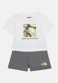 Λευκό παιδικό t-shirt με αφηρημένο λογότυπο North Face και το κείμενο "Never Stop Exploring", σε συνδυασμό με σκούρο γκρι σορτς που φέρει μικρό λογότυπο.