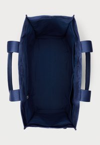 Marinblå tote-väska med en slät tygutsida, två robusta sidhandtag och ett rymligt inre med ett zip-fack.