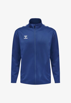 Kék, végigzipzárazható sportdzseki fehér Hummel logóval a mellkason és fehér halszálka csíkokkal a vállakon.