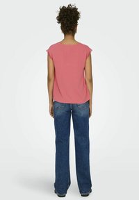 Rosa kortermet topp med blonderkant på skuldrene, kombinert med blå vide jeans. Glatt stoffoverflate; enkel, avslappet design.