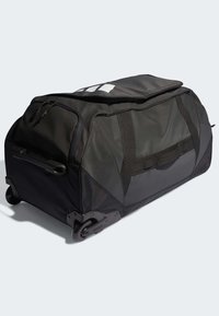 Borsa da viaggio nera a rotoli realizzata in tessuto resistente. Presenta un compartimento principale con cerniera, una maniglia laterale e ruote scorrevoli.