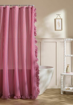 Red and white vertical striped shower curtain with ruffled edges partially covering a white freestanding bathtub in a neutral-tone bathroom.