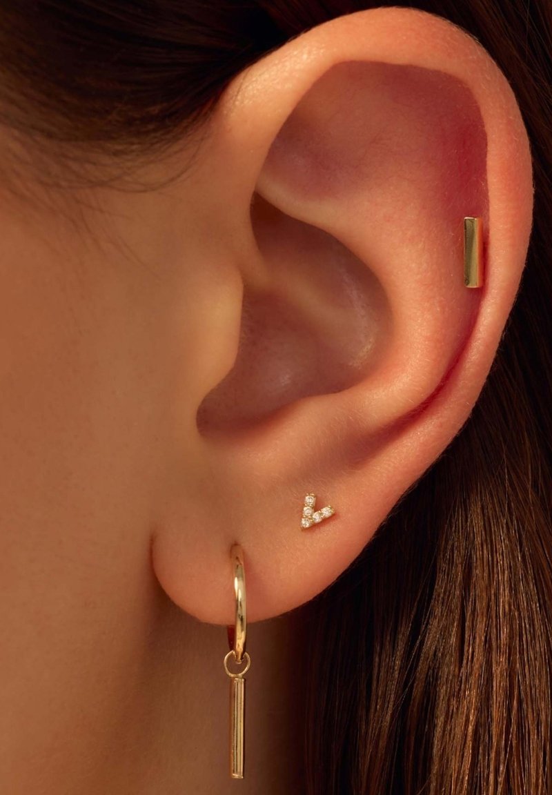 Boucle d'oreille en or avec un pendentif rectangulaire suspendu et une petite puce d'oreille en forme de V ornée de pierres claires.
