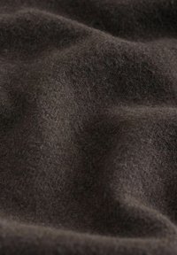 Sötétbarna, puha gyapjú anyag bolyhos textúrával és finom redőkkel, amelyek árnyékokat és mélységet hoznak létre.