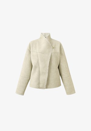 Beige faux suède jas met een off-center knoopsluiting, hoge kraag, zichtbare naden en witte schapenvachtafwerking langs de opening.