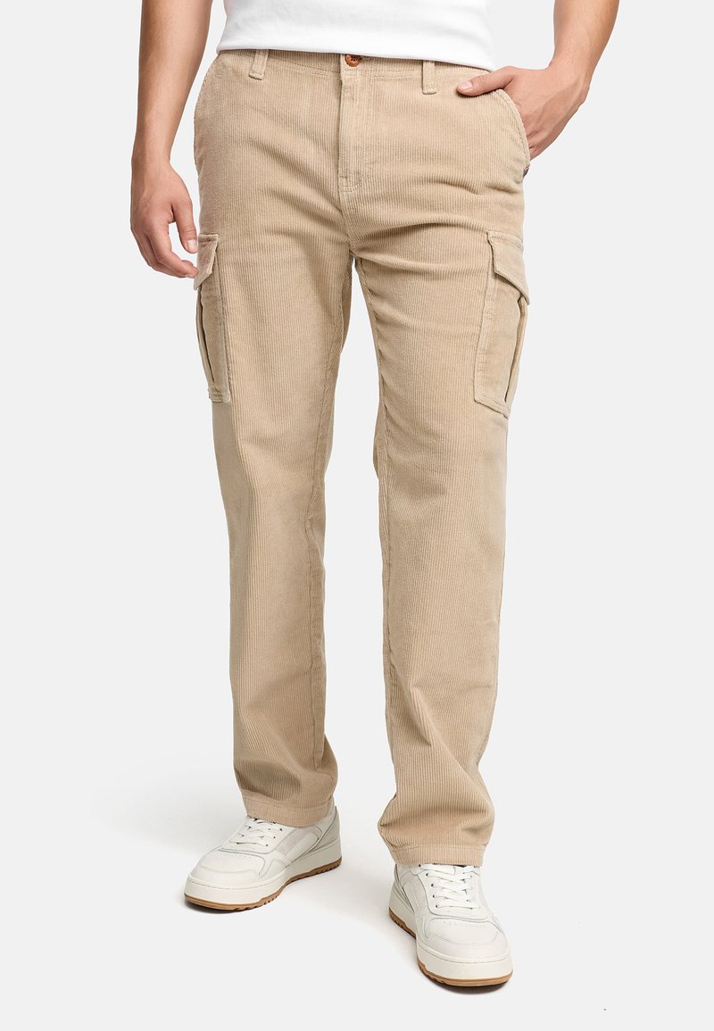 Beiga kabelbyxor i kordflod med sidofickor, rak passform och en texturerad yta. Bärs med vita sneakers.