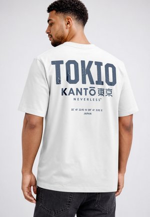 Man wearing white T-shirt with text "TOKIO KANTO" and Japanese characters, standing with back facing the camera.