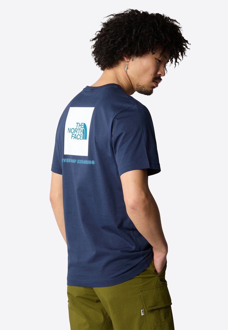 Granatowa koszulka z krótkim rękawem z bawełny z białym prostokątnym logo na plecach, z tekstem "THE NORTH FACE" oraz "NEVER STOP EXPLORING".