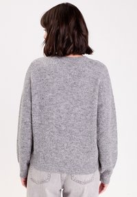 Grå striktrøje med rund halsudskæring og lange, let puffede ærmer. Fremstillet af blødt, struktureret materiale, med en afslappet pasform.