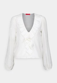 Blouse blanche avec un col en V profond, détail volants à l'avant et manches bouffantes. Confectionnée en tissu léger à la texture lisse.