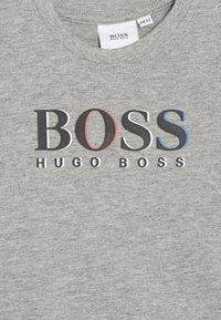 Graues Baumwoll-T-Shirt mit einem schwarzen und roten "BOSS"-Logo und "HUGO BOSS" in Schwarz, mit einer glatten Textur und einem runden Halsausschnitt.