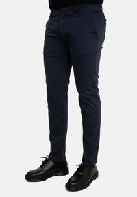 Chinos in cotone blu navy con una vestibilità slim, dotati di passanti per cintura e tasche frontali, abbinati a scarpe nere con lacci per un look completo.