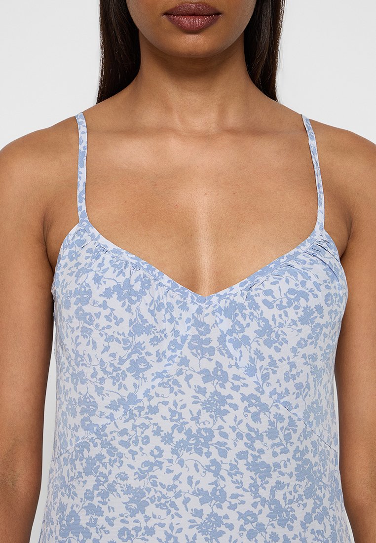 Helles blaues floral bedrucktes Camisole mit dünnen verstellbaren Trägern, V-Ausschnitt und subtiler Textur, ideal zum Schichten oder für warmes Wetter.