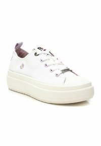 Zapatilla de lona blanca con cordones morados claros y bordados florales. Presenta una suela de goma blanca gruesa y una puntera reforzada.