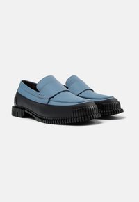 Blauwe leren loafers met zwarte rubberen zolen, met een verhoogde textuur en geribbeld detail. Het ontwerp bevat een gestikte accent op de wreef.