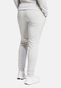 Light gray jogger pants with texture, tapered legs, and side pockets, paired with white athletic shoes. Soft, stretchy fabric.