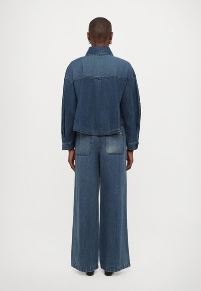 Denim jakna in široke hlače v srednji modri barvi. Jakna ima skrajšan dizajn in sproščen fit. Hlače imajo dve zadnji žep in zbledel detajl.