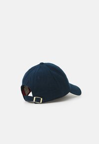 Mørkeblå baseballcap med buet skygge, lavet af bomuld, med en guld metaljusteringstrap bagpå og ventilationshuller.