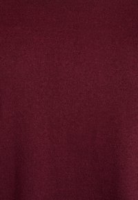 Bordeauxroter Strickstoff mit glatter Textur und feinem Rippmuster, der eine gleichmäßige und intensive Farbe aufweist. Keine sichtbaren Logos oder Verzierungen.