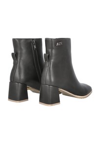 Botines negros de cuero con textura suave, tacón grueso, cremallera trasera y pequeñas tiras para tirar. Presentan un detalle de logotipo en relieve en el lateral.